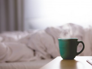 Becher Kaffee auf einem Nachttisch.